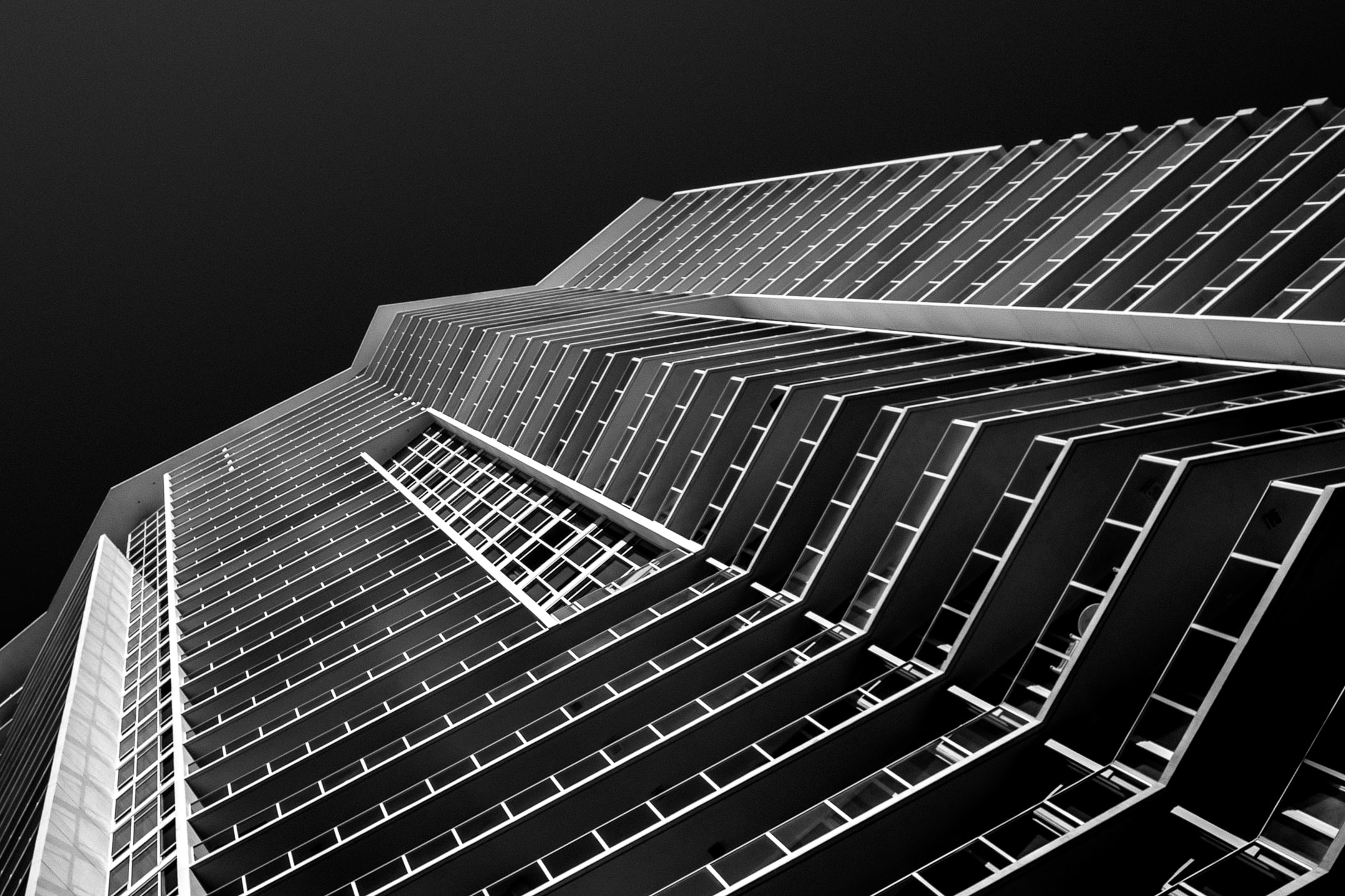 A tilted image of a building with strong vertical lines and symmetry. Monochrome.